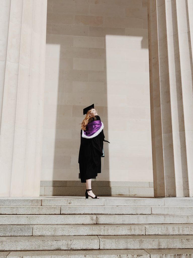 a person in a graduation gown standing on the steps of a building