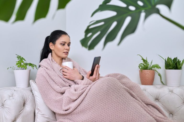 woman covered in blanket surrounded by plants