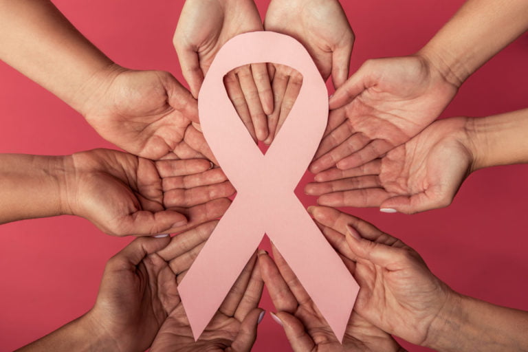 Women against breast cancer. Cropped image of woman holding a pink paper ribbon, on red background