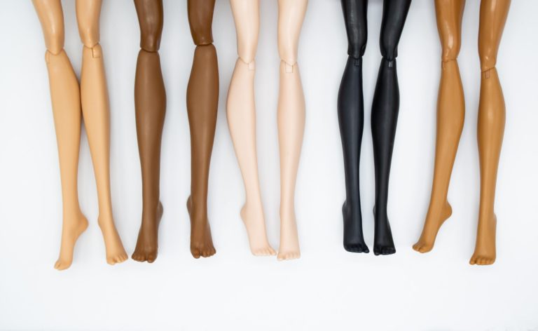 Legs of dolls representing different races on a white background. friendship, health, beauty