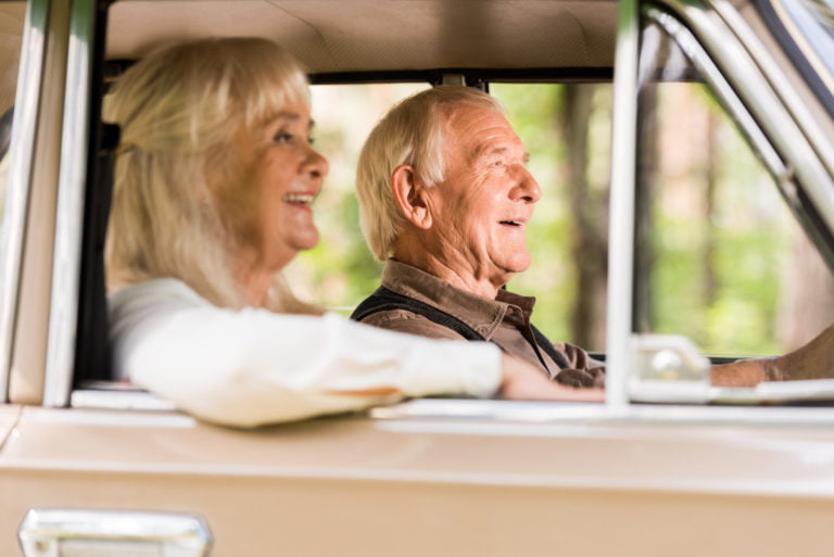 side view of handsome senior couple driving beige vintage car